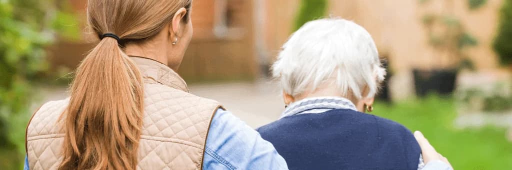 A care worker accompanying an older person outdoors